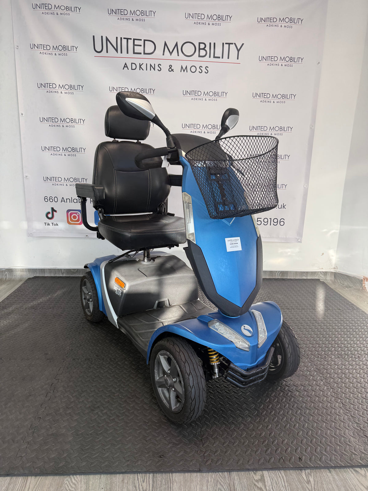Blue mobility scooter front with black seat, headrest, and wire basket