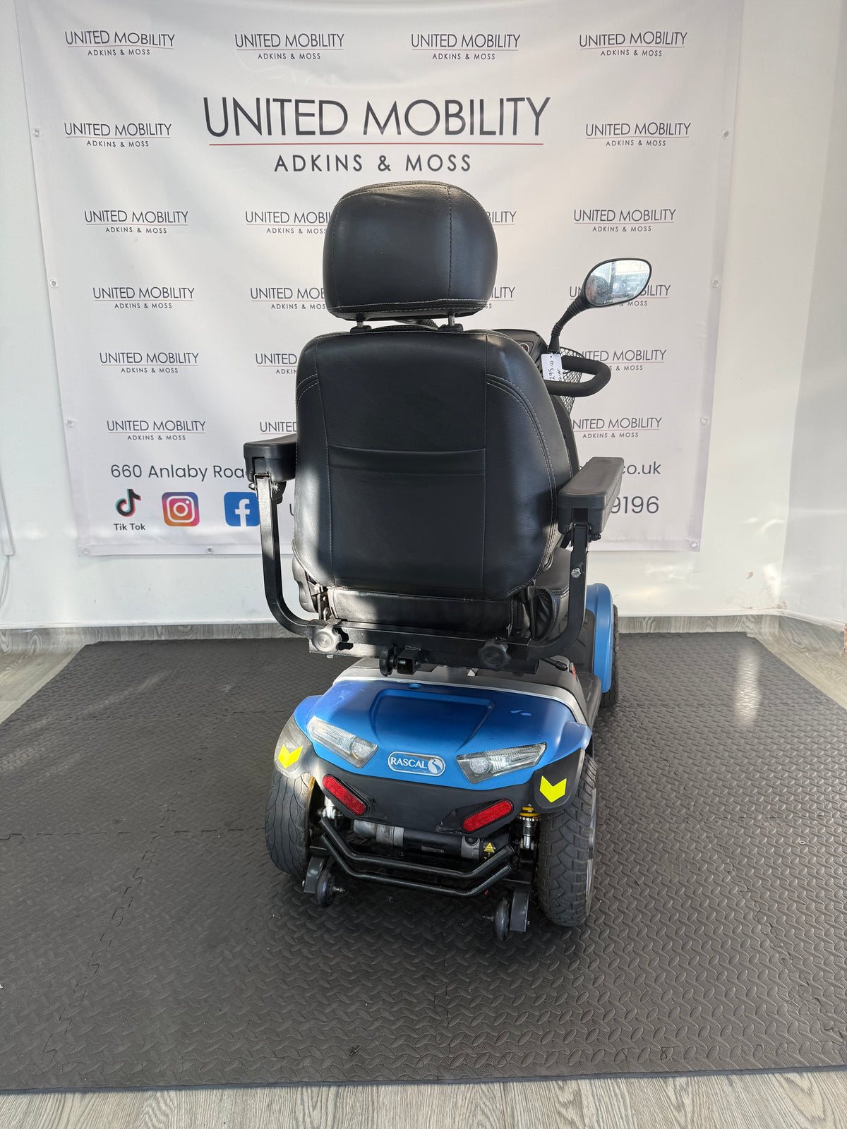 Blue mobility scooter rear view with black seat, headrest, and rear lights