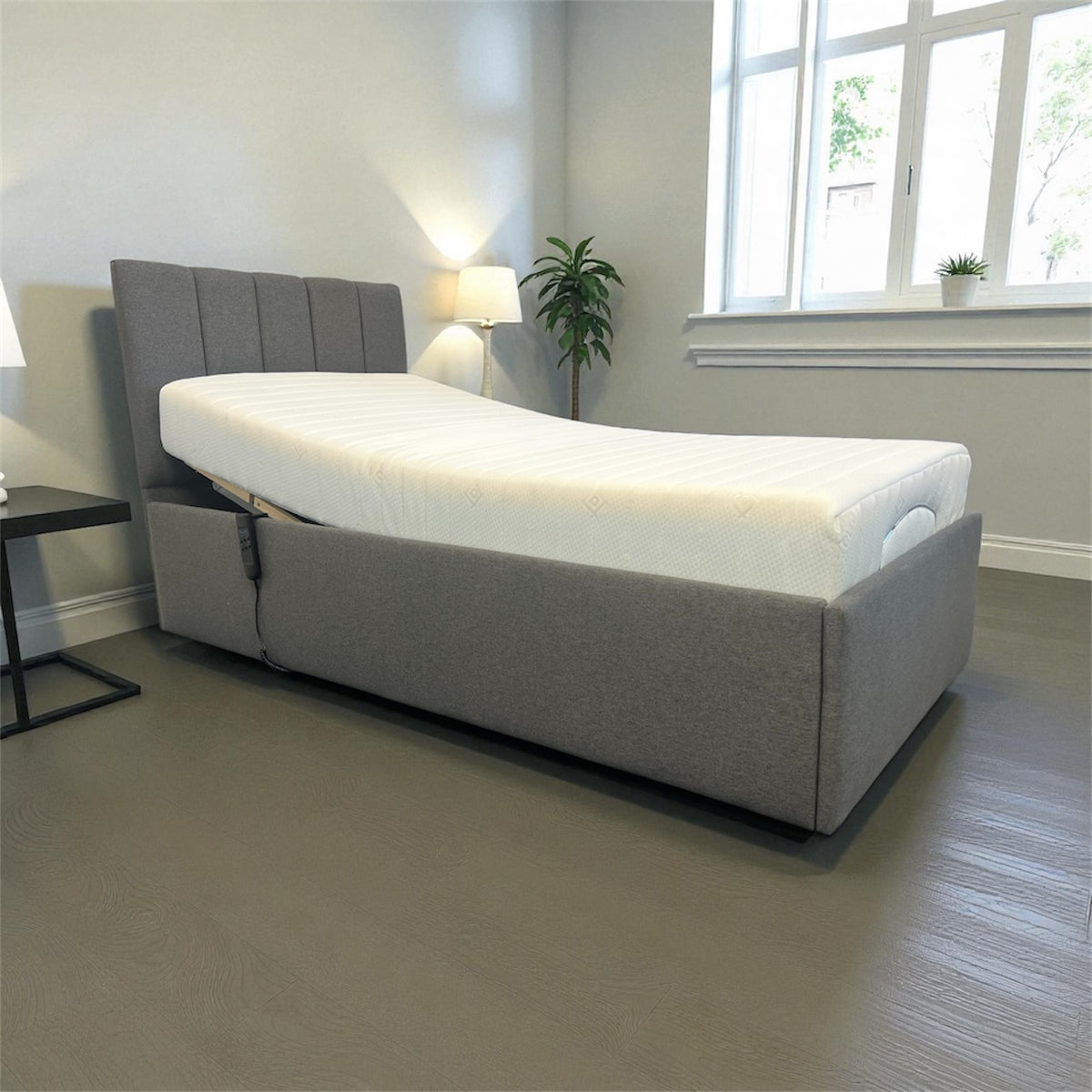 Modern grey fabric adjustable bed with white mattress and padded headboard, corner view