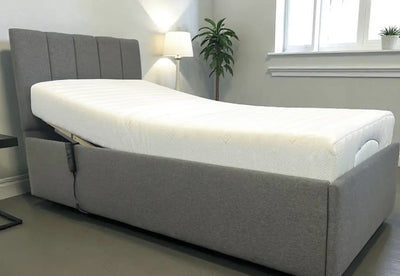 Grey upholstered bed frame with white mattress and tall headboard panels, adjustable base