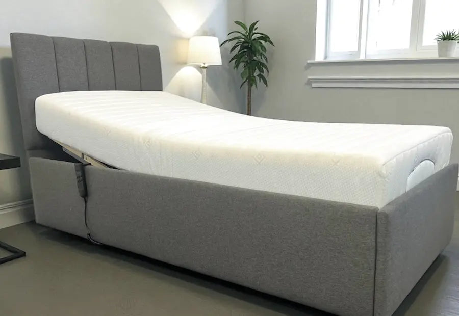 Grey upholstered bed frame with white mattress and tall headboard panels, adjustable base