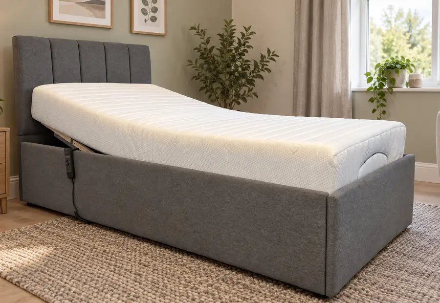 Low-profile grey upholstered bed with white mattress, padded side arms and panel headboard