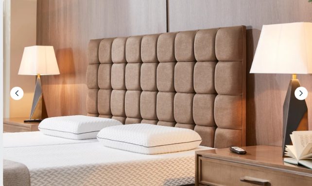 Modern hotel room featuring a padded headboard, double bed, and stylish bedside lamps.
