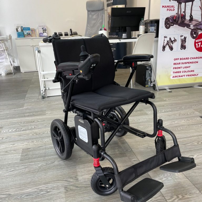 A folding electric wheelchair with armrests and footrests, set in an office-like environment.