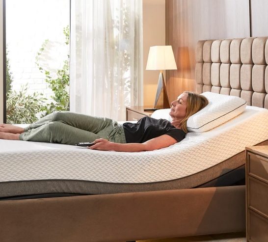 Woman relaxing on an adjustable mattress in a well-lit bedroom.